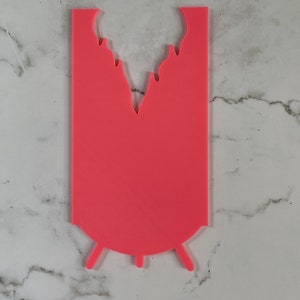 May include: A pink silicone mold shaped like a dripping ice cream cone with a rounded bottom and three legs.