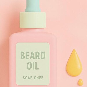 May include: A pink bottle of beard oil with a light green dropper and a light green label that reads "BEARD OIL" and "SOAP CHEF". A yellow oil droplet and a smaller droplet are next to the bottle on a pink background.