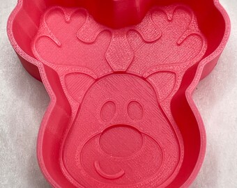 Op de afbeelding: Een roze plastic rendier koekjesvormpje met een gedetailleerd ontwerp. De vormpje heeft een groot hoofd met gewei, een grote neus en twee ogen.