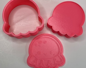 May include: Three pink plastic cookie cutters shaped like jellyfish. The cutters are designed to create a 3D jellyfish shape.