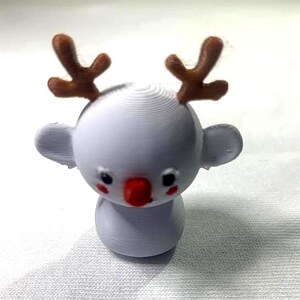 以下が含まれることがあります： 茶色の角、黒い目、赤い鼻を持つ白いコアラの置物。コアラは小さく丸い耳と丸い体を持っています。置物は3Dプリントされている可能性があり、白い表面に置かれています。