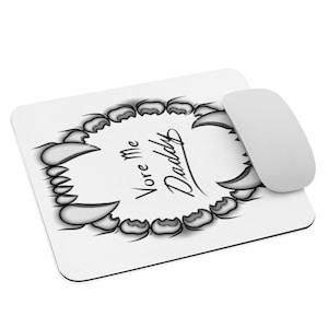 May include: White rectangular mousepad with a stylized black and gray toothy design and the words "Vore Me Daddy" in a script font. A white wireless mouse is positioned on the right side of the mousepad.