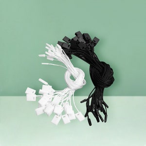 Puede incluir: Primer plano de dos paquetes de cuerda con etiquetas de plástico. Un paquete es negro y el otro es blanco.