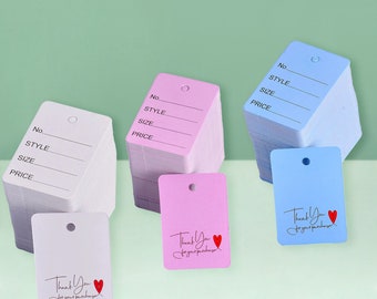 May include: A stack of blank white, pink, and blue hang tags with a hole at the top. The tags have lines for writing "No.", "Style", "Size", and "Price". Some tags have the text "Thank You for your purchase" with two red hearts.