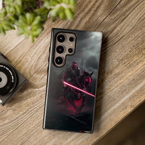 May include: A black phone case with a dark image of a knight riding a horse with a red lightsaber. The phone case has a black camera bump with three camera lenses.