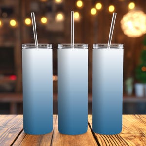 May include: Three stainless steel tumblers with a blue to white ombre design. Each tumbler has a clear plastic straw.