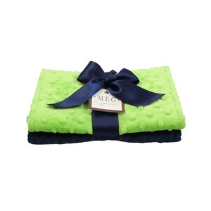 May include: A green and navy blue baby blanket set with a navy blue satin ribbon bow and a tag that says "MEG original".
