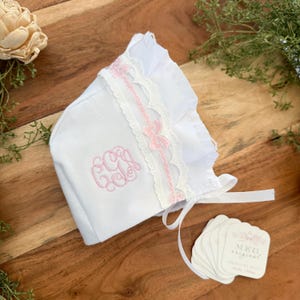 Babykapje met monogram, kant en ruches en strikjes, ideaal voor pasgeboren babyfotografie.