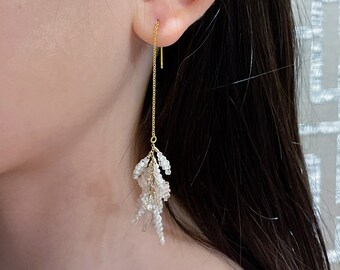 May include: Gold chain earrings with a cluster of white beads dangling from the bottom.