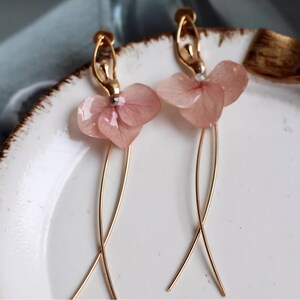 A close-up detail shot of the pink resin flower earrings, showing the delicate texture of the real pressed flower petals.