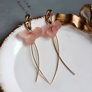 A close-up detail shot of the pink resin flower earrings, showing the delicate texture of the real pressed flower petals.