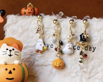 May include: Gold-toned Halloween-themed earrings with dangling charms. One pair features a ghost, a pumpkin, and a witch's hat. The other pair has a ghost and a pumpkin. The earrings are displayed with decorative figurines.