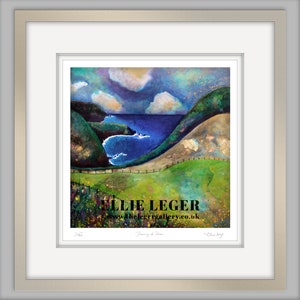 May include: Framed art print of a coastal landscape with rolling green hills, a blue sea, and a cloudy sky. The artwork features a fence in the foreground and the artist's signature. The text "Ellie Leger" is visible.