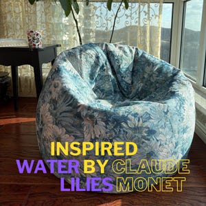 May include: A large, round bean bag chair with a floral print inspired by Claude Monet's Water Lilies. The fabric features a blue and white background with pink and green floral accents. The text "INSPIRED WATER BY CLAUDE LILIES MONET" is printed on the chair.