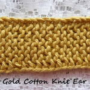 May include: Pale Gold Cotton Knit Ear Saver with two gold buttons.