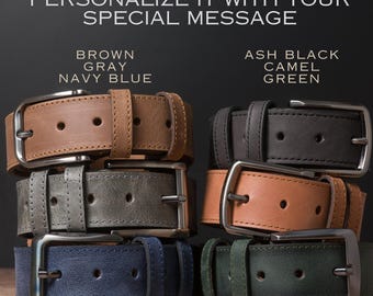 May include: Six leather belts stacked in two columns, featuring silver-toned metal buckles and multiple adjustment holes. The colours include brown, grey, navy blue, ash black, camel, and green. Text reads: PERSONALIZE IT WITH YOUR SPECIAL MESSAGE.