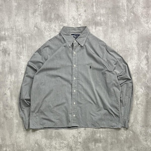 May include: A light gray button-down shirt with long sleeves. The shirt has a button-down collar and a small embroidered logo on the chest. The shirt is made of a soft, woven fabric.