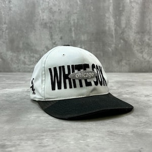 Peut inclure: Une casquette de baseball blanche avec une visière noire et le texte brodé en noir WHITE SOX. Un petit écusson ovale gris avec le mot chicago est centré sur le devant. Un logo noir est brodé sur le côté de la calotte blanche.