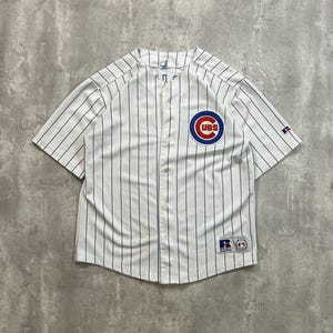 May include: White baseball jersey with blue pinstripes. The jersey features the Chicago Cubs logo on the chest and a Russell Athletic logo on the sleeve. The jersey has a button-up front and short sleeves.