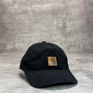 Può includere: Cappellino da baseball nero con visiera curva. Il cappellino presenta una piccola toppa quadrata marrone con il logo Carhartt sul davanti. Realizzato in tessuto resistente, ha un design a basso profilo.