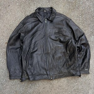 May include: A dark brown leather jacket featuring a classic fold-down collar, a full-length front zip closure, two vertical side pockets, and a single horizontal welt pocket on the upper left chest. The jacket has long sleeves with cuffs.