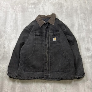 May include: A black work jacket with a brown corduroy collar. The jacket has two chest pockets, two lower pockets, and a small square logo patch on the right chest. The jacket is made of a durable, worn material.