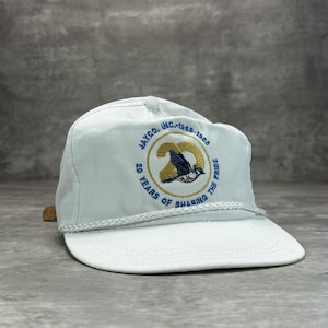 May include: White baseball cap with a curved brim and a rope detail. The cap features an embroidered logo with the text "JAYCO, INC. 1968-1988" and "20 YEARS OF SHARING THE PRIDE" around a bird emblem.