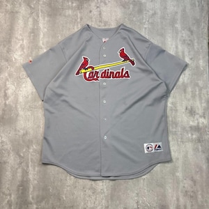 May include: Grey baseball jersey featuring the word "Cardinals" in red script. Two red cardinal birds are perched on a yellow baseball bat. The jersey has short sleeves and a button-up front.