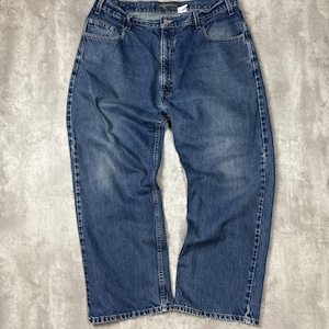 May include: A pair of medium-wash blue denim jeans. The jeans have a classic five-pocket design, a button and zipper closure, and a straight leg fit. The denim shows some fading and wear, giving them a vintage look.
