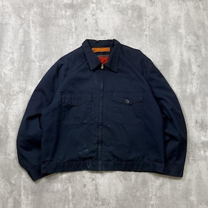 May include: A navy blue work jacket with a full zip, two front pockets, and a collared neckline. The jacket has a red lining and shows signs of wear, suggesting it is vintage. The jacket's style is reminiscent of classic workwear.