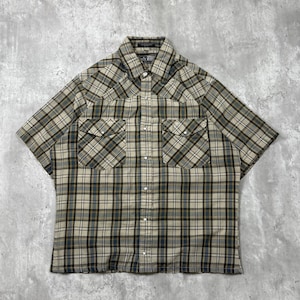 May include: A short-sleeve button-down shirt featuring a plaid pattern in shades of beige, dark blue, and black. The shirt includes a pointed collar, two chest pockets with button-down flaps, and a front placket with visible metal snap buttons.