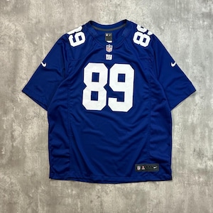Pode incluir: Uma camisola de futebol azul com o número 89 branco na frente e nas costas, e em cada ombro. Os logótipos da NFL e da Nike são visíveis na camisola.