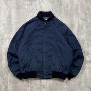 May include: A navy blue bomber jacket with a black ribbed collar, cuffs, and hem. It has a zip-up front and two front pockets. A classic style of outerwear.