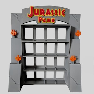 Può includere: Uno scaffale espositivo grigio con quattro ripiani orizzontali e divisori verticali. L'arco superiore riporta la scritta JURASSIC PARK in rosso e giallo. Quattro decorazioni arancioni a forma di fiamma sono fissate ai pilastri laterali.