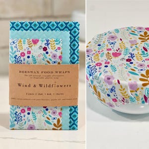 Puede incluir: Envoltorios de alimentos de cera de abeja con diseño floral. Los envoltorios son en tonos de azul, rosa y blanco. El paquete incluye tres envoltorios de diferentes tamaños: 20x20 cm, 23x23 cm y 25x25 cm. El texto en el paquete dice "Wind & Wildflowers."