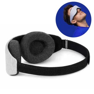 Può includere: Una mascherina per dormire grigio chiaro e grigio antracite con un design sagomato, coppe oculari imbottite e un cinturino elastico nero regolabile. La mascherina è realizzata con un esterno in tessuto testurizzato e una fodera scura.