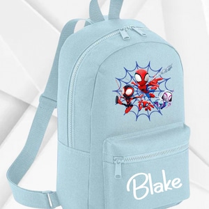 May include: A pale blue backpack with a Spider-Man design and the name "Blake" in white script. The backpack has a front pocket, adjustable straps, and a top handle. The Spider-Man graphic features several characters within a web.