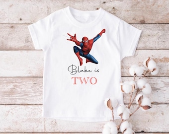 Puede incluir: Camiseta blanca con un gráfico de Spiderman rojo y azul y el texto "Blake is TWO" impreso en ella.