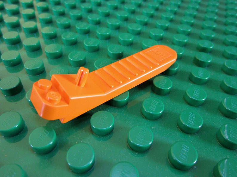 An orange LEGO separator displayed on a green LEGO baseplate.