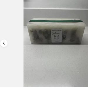 May include: A white rectangular candle with a green label that reads "Hotel Collection Scandinavian Forest" and a green ribbon around the top.