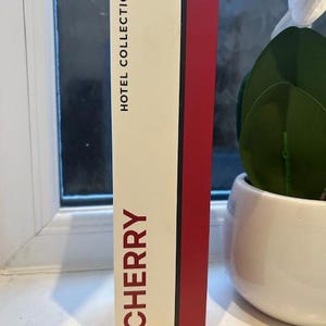 May include: A white and red box with the text "HOTEL COLLECTION" and "CHERRY REED DIFFUSER" on it.