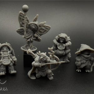 May include: A set of seven gray painted miniature figurines of fantasy creatures. The figures are posed in various action poses and include a winged fairy, a warrior with a sword, a creature with a bow and arrow, a creature with a staff, a creature with a bag, a creature with a staff and a creature with a pipe.