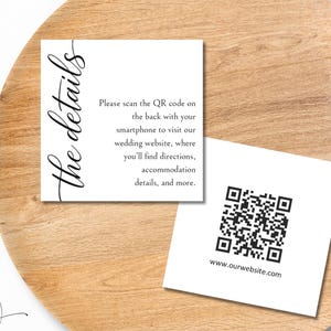 May include: Two white square cards with black text and a QR code sit on a wooden plate. One card reads "the details" in cursive. The other card has a QR code and the website address. Floral accents surround the plate.