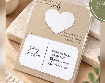 Puede incluir: Una funda de plástico transparente que contiene una tarjeta color canela con un corazón de semillas plantable blanco de 5 cm. La tarjeta incluye el texto: YOUR REFERRALS PLANT seeds & GROW ROOTS IN OUR BEAUTIFUL COMMUNITY. Tarjeta de visita de Stacey Langstrom, Golden Key Realty.
