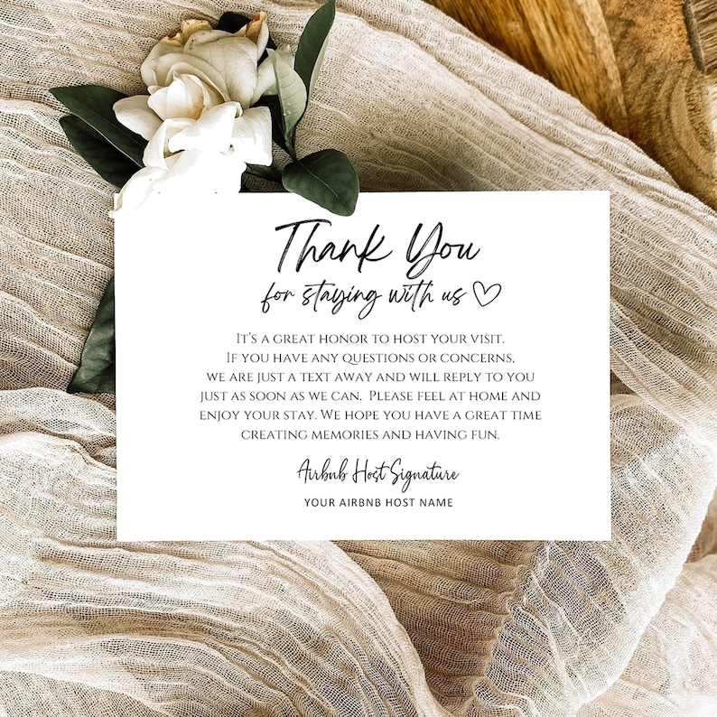 May include: A white card with a thank you message for guests staying at an Airbnb. The message reads "Thank You for staying with us." and includes a heart symbol. The card also includes a message about contacting the host if guests have any questions or concerns. The card is on a beige textured background.