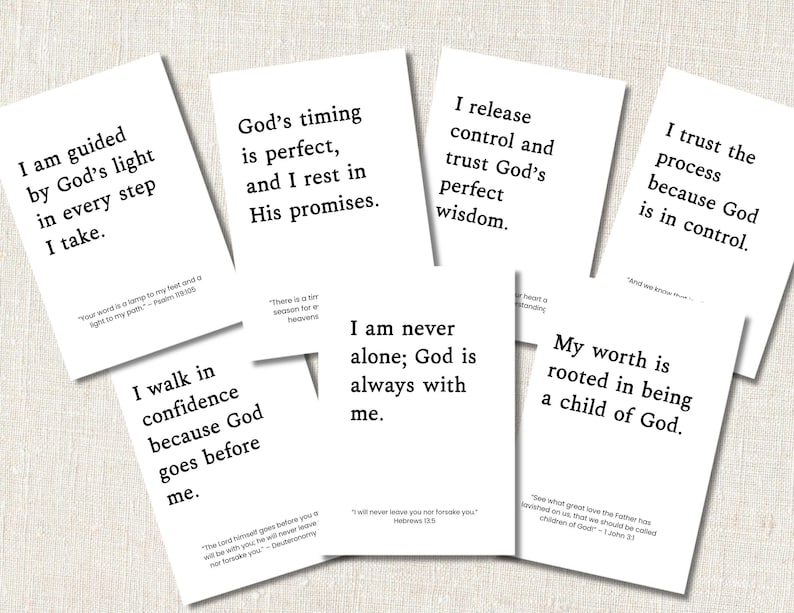 May include: A collection of white cards with inspirational quotes in black text. The cards feature phrases like "I am guided by God's light" and "God's timing is perfect." The cards are arranged on a light beige surface.