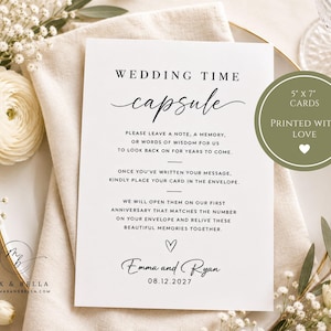 May include: A white rectangular wedding time capsule card with black text that reads: WEDDING TIME capsule, PLEASE LEAVE A NOTE, A MEMORY, OR WORDS OF WISDOM FOR US TO LOOK BACK ON FOR YEARS TO COME. 5" x 7" CARDS PRINTED WITH LOVE, Emma and Ryan 08.12.2027.