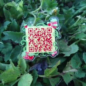 May include: A green and yellow sticker with a QR code and strawberries. The sticker is on a bed of green leaves.