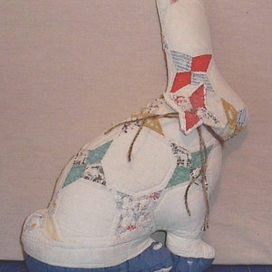 May include: A white patchwork bunny rabbit with blue feet. The bunny is made from different fabrics and has a red, white and blue patchwork design on its back.