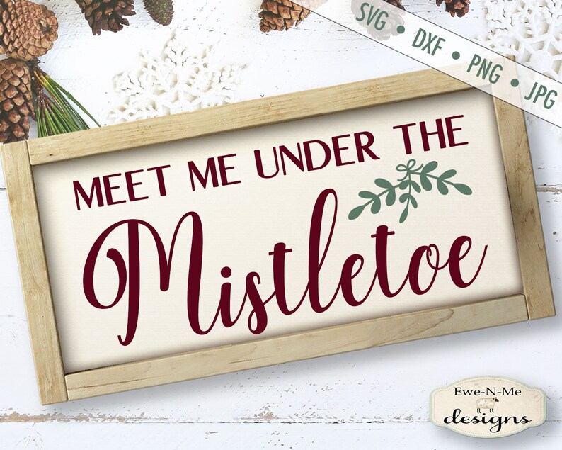 K&ouml;nnte beinhalten: Ein rechteckiges Holzschild mit dem Text "MEET ME UNDER THE Mistletoe" in burgunderfarbener Schrift. Das Schild hat einen cremefarbenen Hintergrund und einen hellbraunen Holzrahmen. Gr&uuml;ne Mistelzweige befinden sich &uuml;ber dem Wort "Mistletoe".
